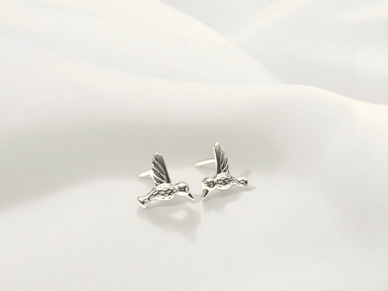 A pair of sterling silver stud earrings with a butterfly back, displayed against a white fluffy background.