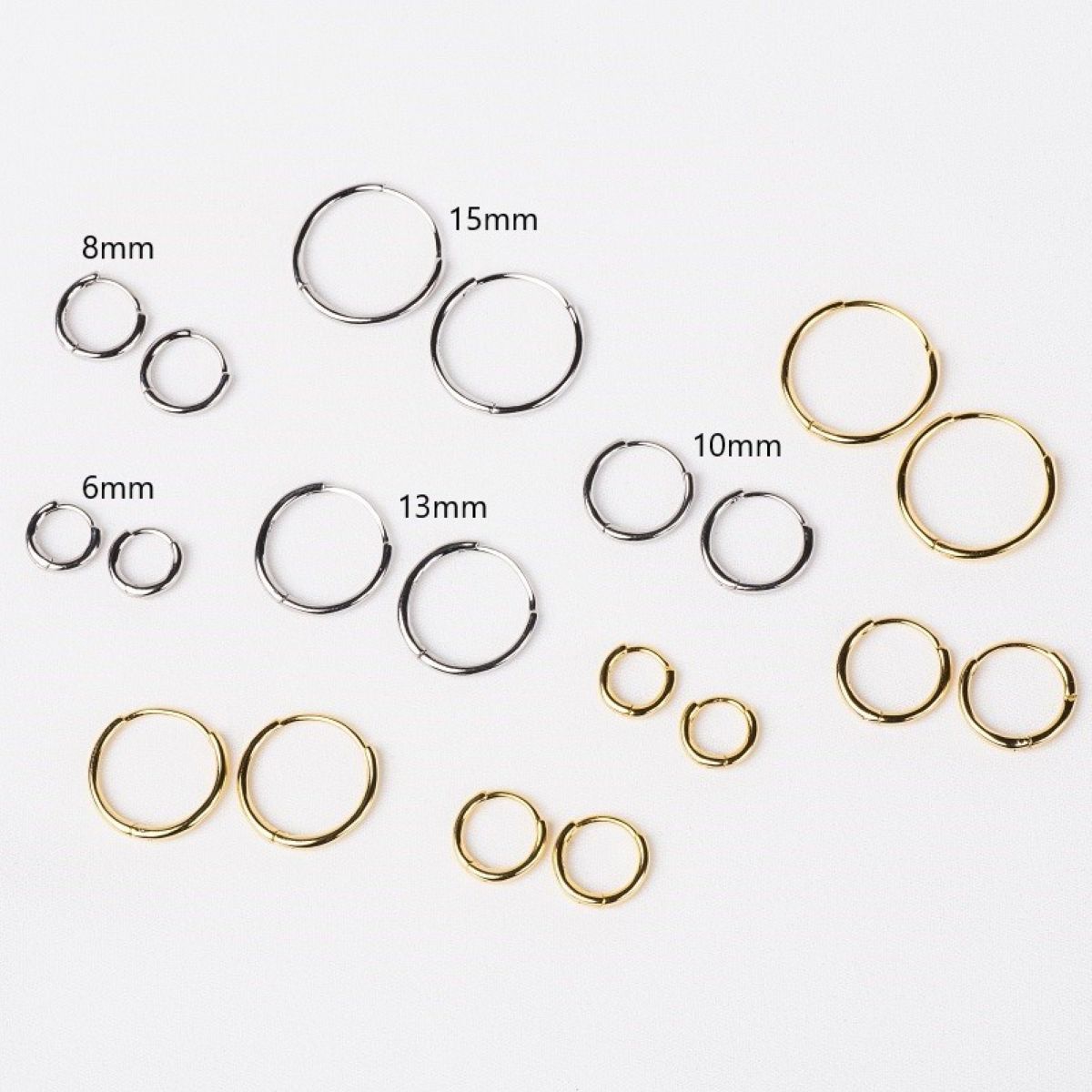 A collection of plain huggie earrings in sterling silver, displayed in various sizes with the diameters marked.