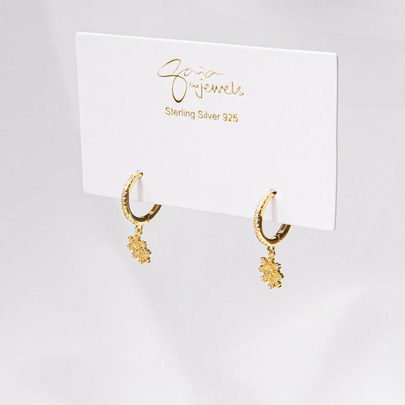 A pair of gold vermeil hoop earrings with a floral detail, displayed on a white card with the brand name 'Gaia'