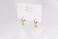 A pair of gold vermeil hoop earrings with a floral detail, displayed on a white card with the brand name 'Gaia'