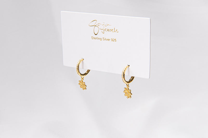 A pair of gold vermeil hoop earrings with a floral detail, displayed on a white card with the brand name 'Gaia'