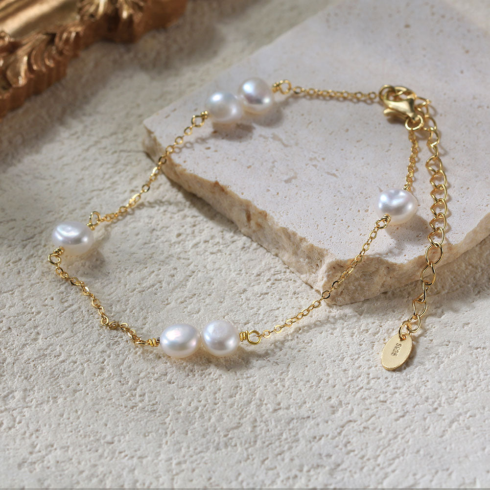 Gold bracelet with pearls on a textured surface