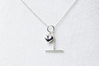 A sterling silver necklace with a small heart pendant, on a white background.