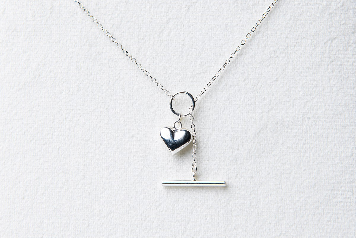 A sterling silver necklace with a small heart pendant, on a white background.