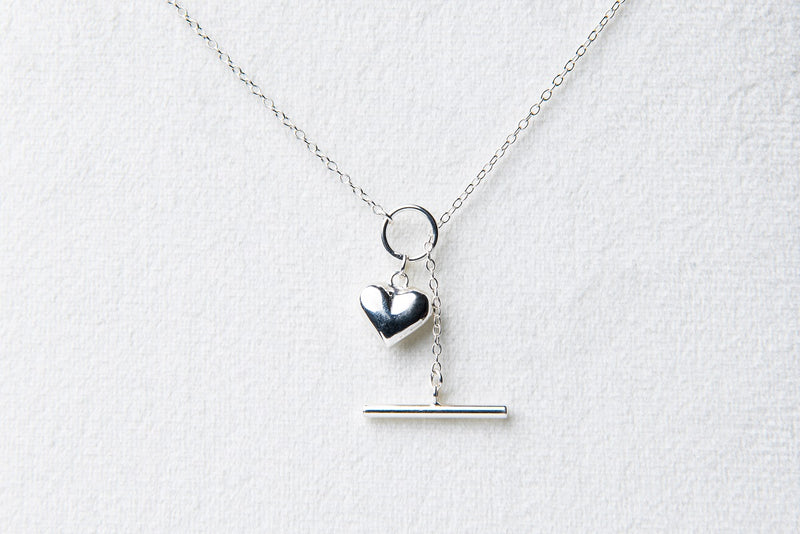 A sterling silver necklace with a small heart pendant, on a white background.