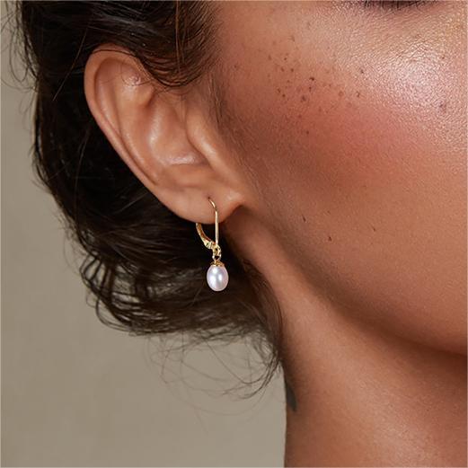 an earlobe wearing the drop pearl earrings