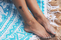 Woman wearing a gold anklet featuring a heart shaped charm