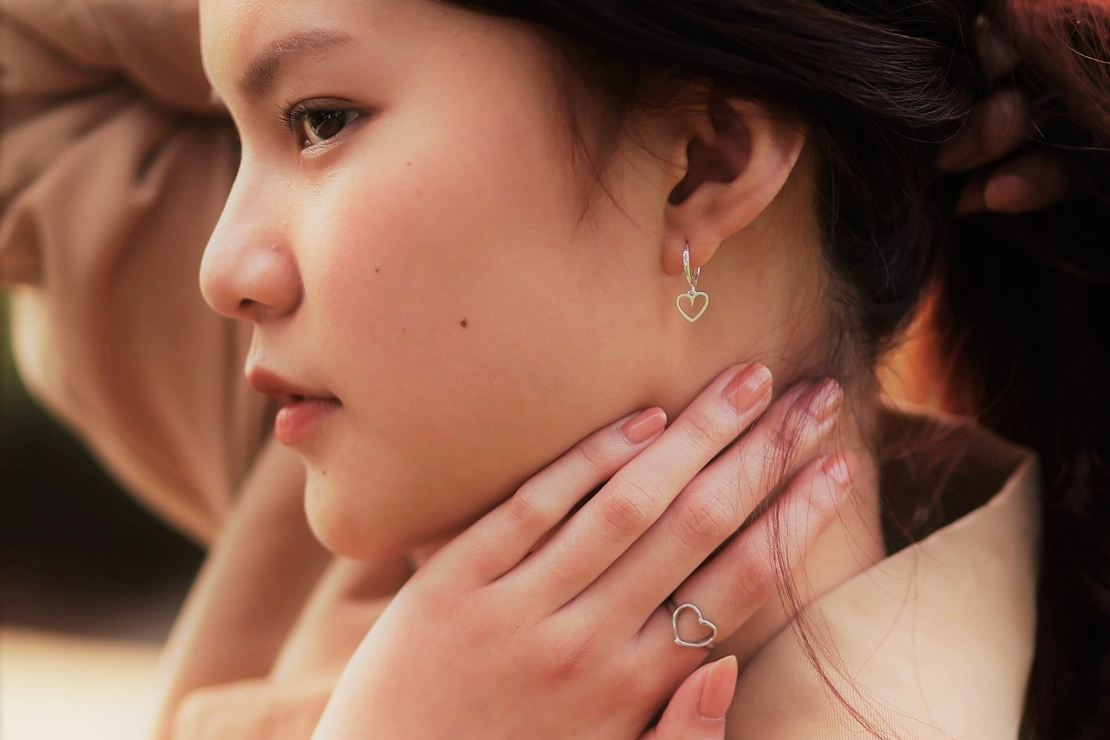 Side profile wearing love heart dangle silver earrings