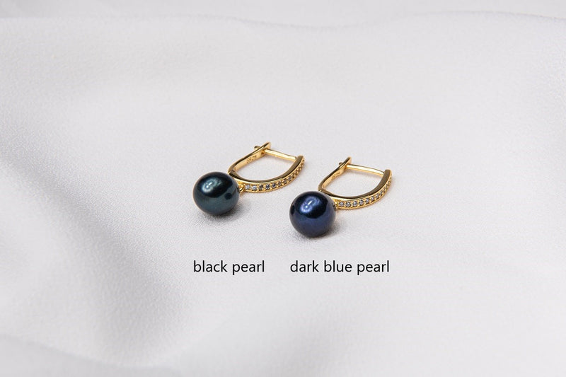 Two pearl earrings featuring gold vermeil. One has a black pearl, one has a dark blue pearl. On a white background with labelling for each different color.