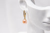 A gold vermeil earring featureing cubic zirconias and a champagne pearl displayed on a white mannequin head