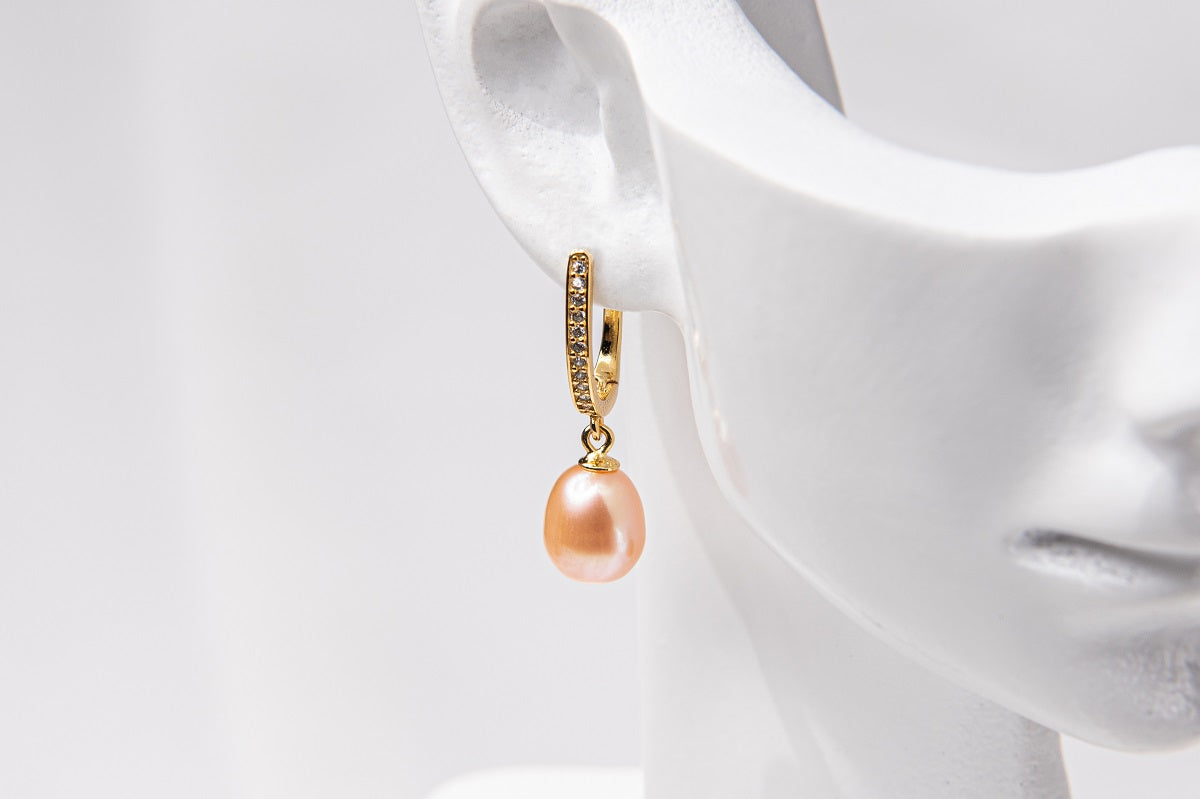 A gold vermeil earring featureing cubic zirconias and a champagne pearl displayed on a white mannequin head