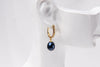 A gold vermeil earring featureing cubic zirconias and adark blue pearl displayed on a white mannequin head