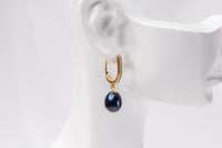 A gold vermeil earring featureing cubic zirconias and adark blue pearl displayed on a white mannequin head