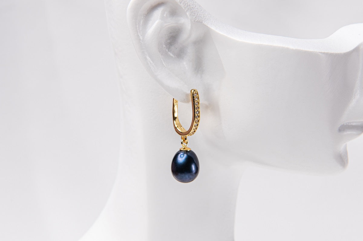 A gold vermeil earring featureing cubic zirconias and adark blue pearl displayed on a white mannequin head