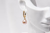 A gold vermeil earring featureing cubic zirconias and a rose pearl displayed on a white mannequin head