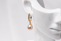 A gold vermeil earring featureing cubic zirconias and a rose pearl displayed on a white mannequin head