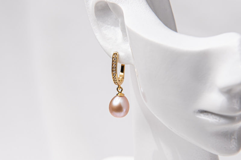 A gold vermeil earring featureing cubic zirconias and a rose pearl displayed on a white mannequin head