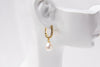 A gold vermeil earring with a pearl displayed on a white mannequin head