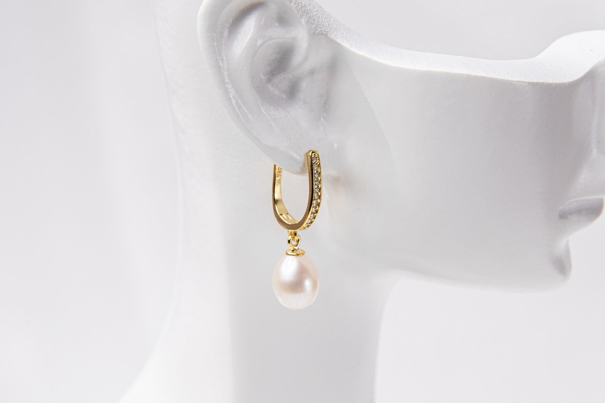 A gold vermeil earring with a pearl displayed on a white mannequin head