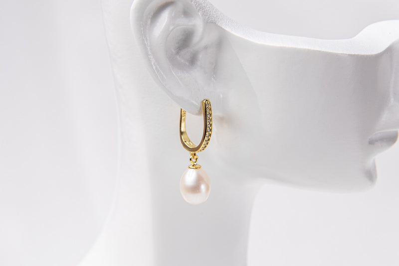 A gold vermeil earring with a pearl displayed on a white mannequin head