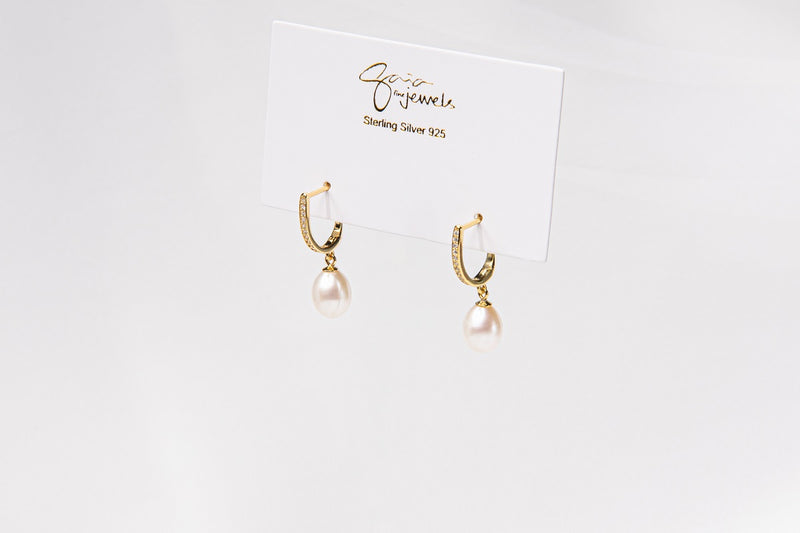 A pair of gold vermeil earings with cuic zirconias and champagne pearls on a white display card and white background