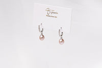 A pair of silver earings with cuic zirconias and champagne pearls on a white display card and white background