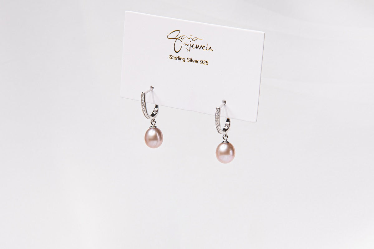 A pair of silver earings with cuic zirconias and champagne pearls on a white display card and white background