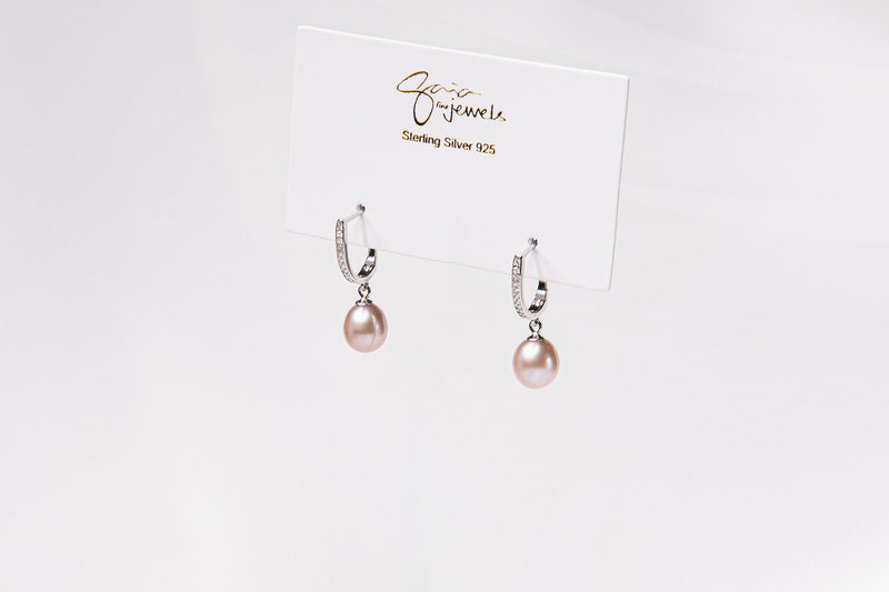 A pair of silver earings with cuic zirconias and champagne pearls on a white display card and white background