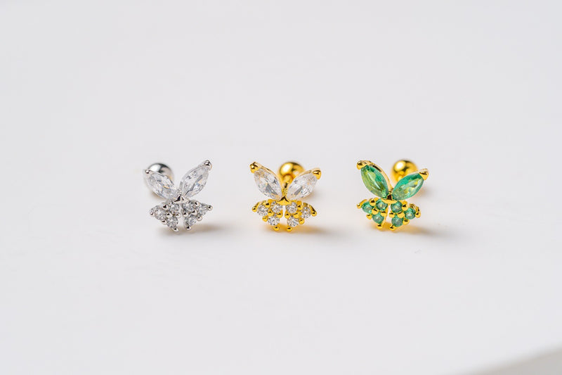 A silver and two gold earrings in the shape of a fairy featuring cubic zirconias on a white background