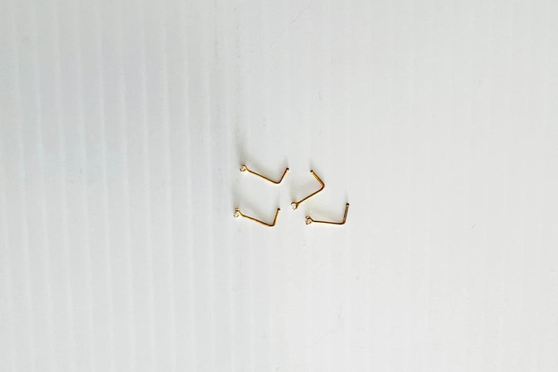 A close-up image of a sterling silver nose stud with gold vermeil rods and an L-shaped hook.