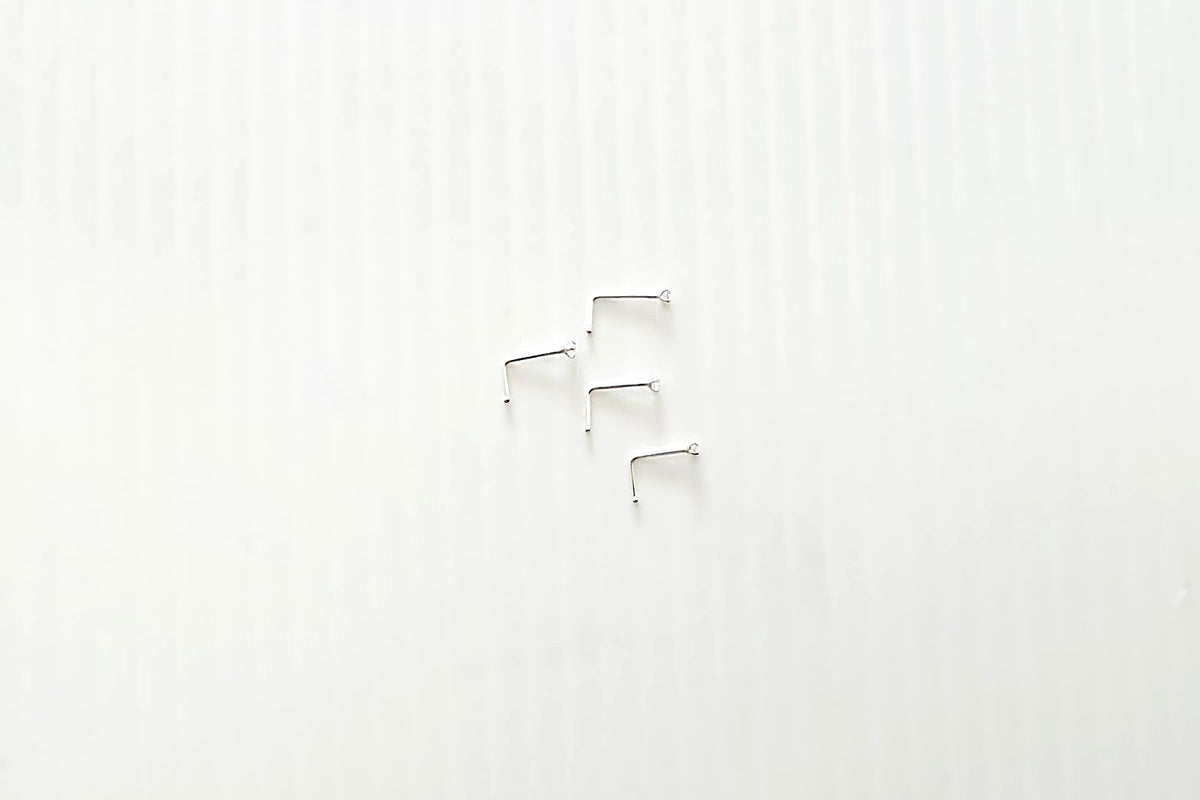 A close-up image of a sterling silver nose stud with an L-shaped hook, showing the texture of the silver and the slight sheen.