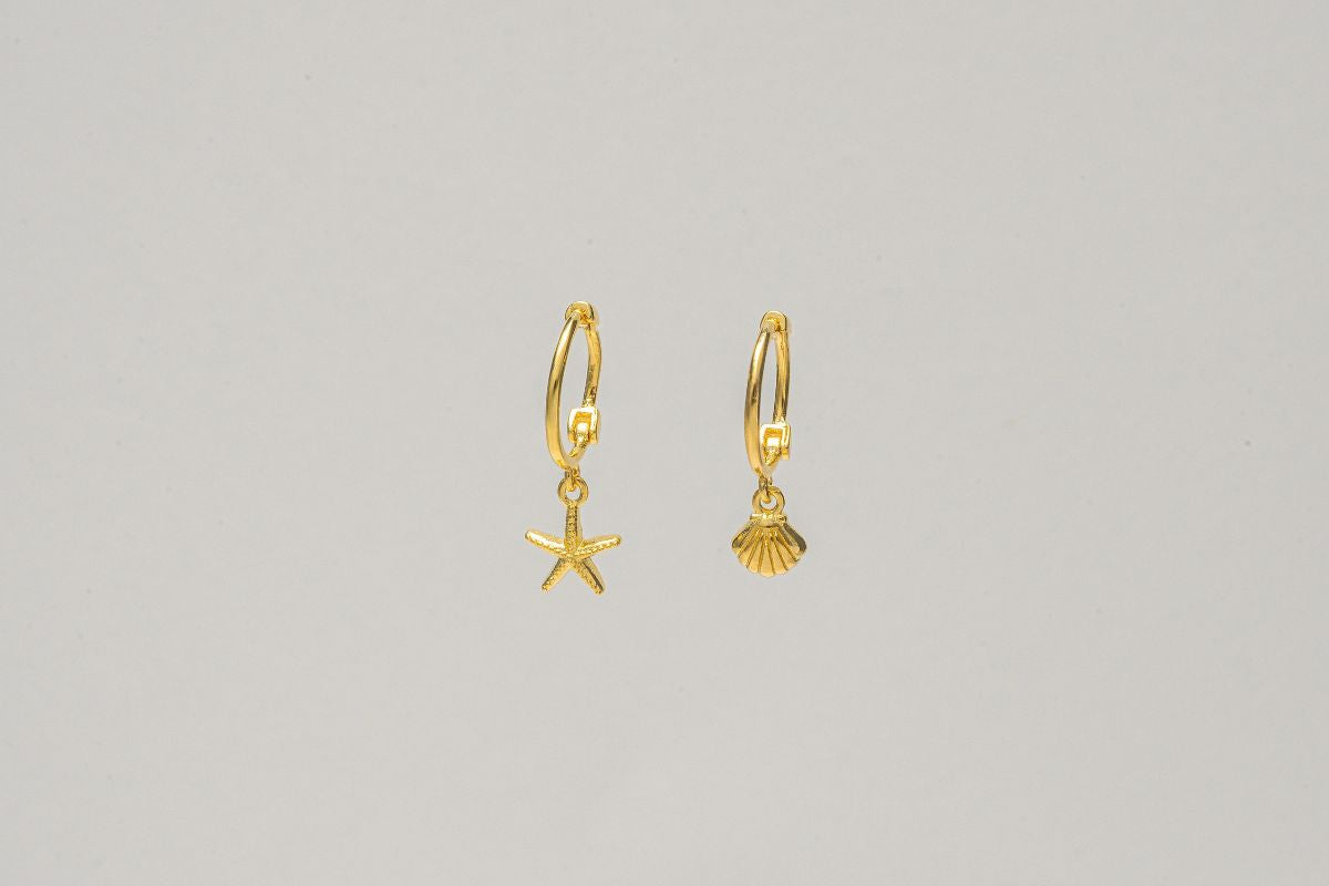 A pair of gold vermeil hoop earrings with a starfish and shell dangle, displayed against a plain background.
