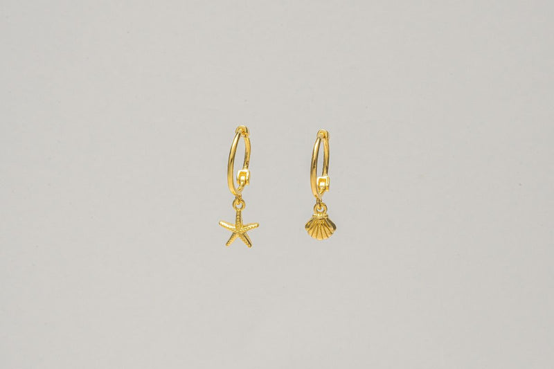 A pair of gold vermeil hoop earrings with a starfish and shell dangle, displayed against a plain background.