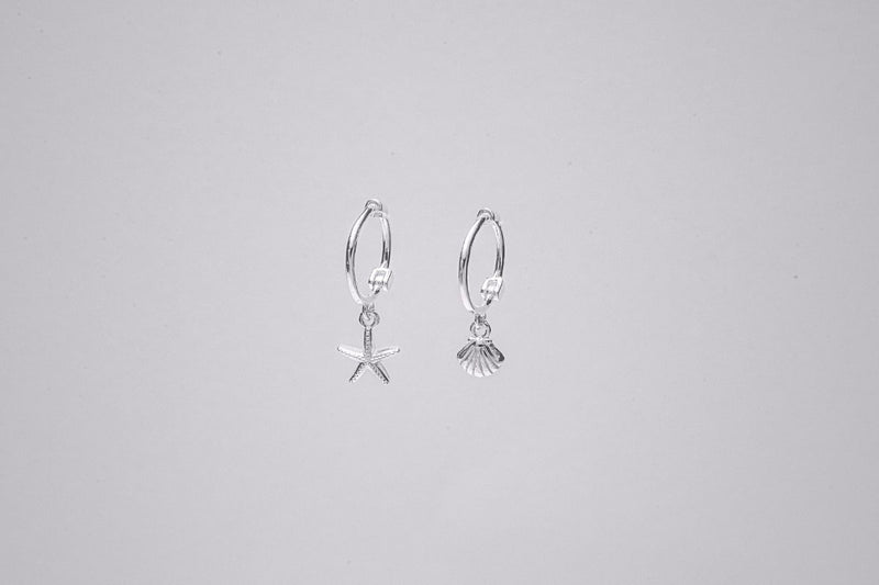 A pair of Silver hoop earrings with a starfish and shell dangle, displayed against a plain background.