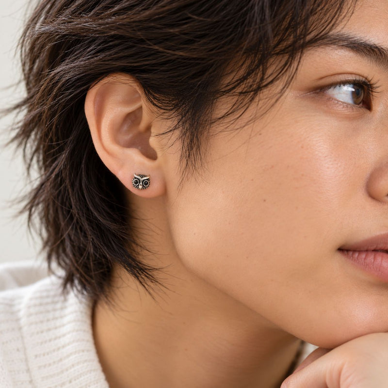 a model wearing a sterling silver owl stud
