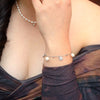 A sterling silver bracelet with freshwater pearl and shell-shaped silver elements around wrist