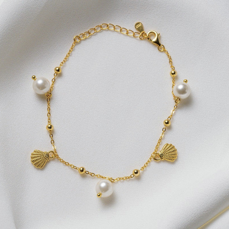 A sterling silver gold vermeil bracelet with freshwater pearl and shell-shaped silver elements