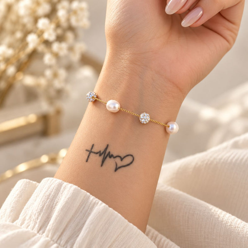 tattooed wrist wearing elegant pearl
