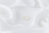 A white, baroque-shaped pearl ring with a gold band, displayed on a white fabric surface.
