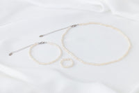 A set of elegant pearl jewellery, ring, necklace and bracelet all matching on a white background.