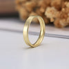 Gold ring on a light surface with blurred dried flowers in the background