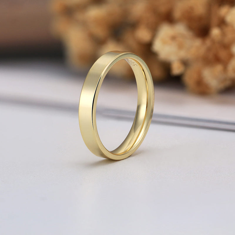 Gold ring on a light surface with blurred dried flowers in the background