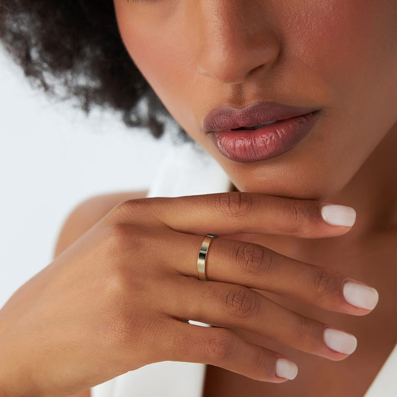 Close-up of a woman's hand with a gold ring and pink lipstick on a white background