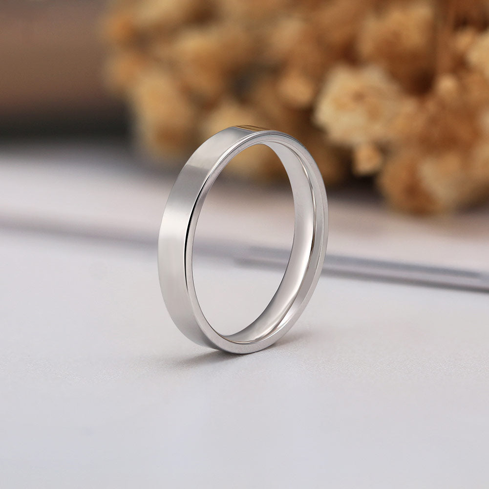 Silver ring on a light gray surface with blurred natural background