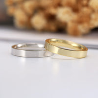 Gold and silver rings on a light background with blurred natural elements.