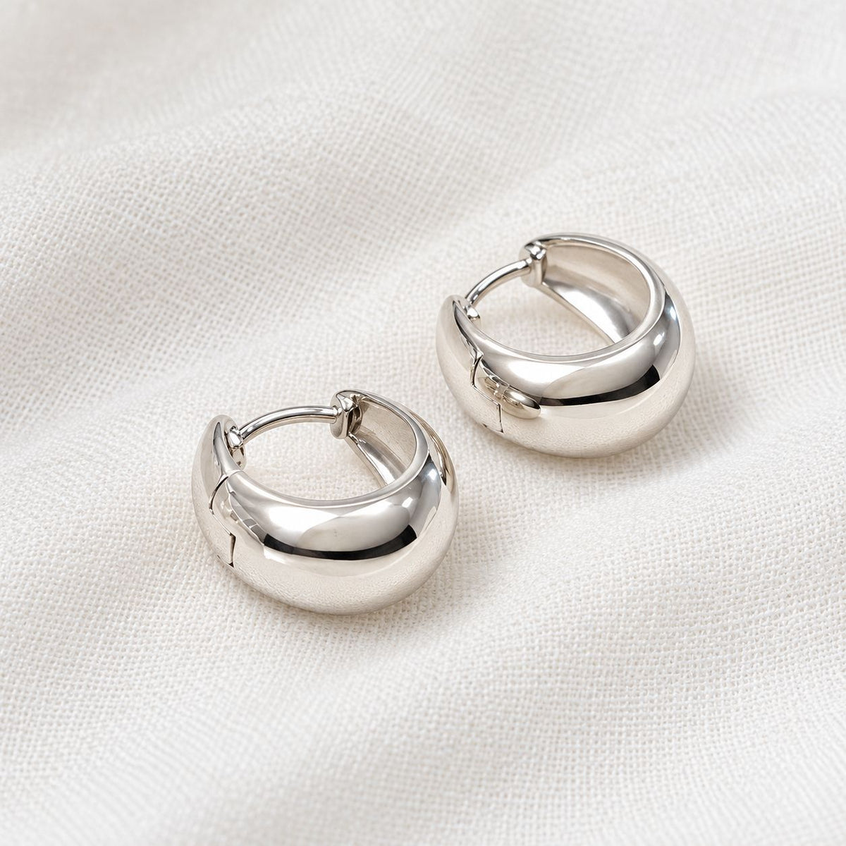 PolishedSilverHuggieEarringsonLinen