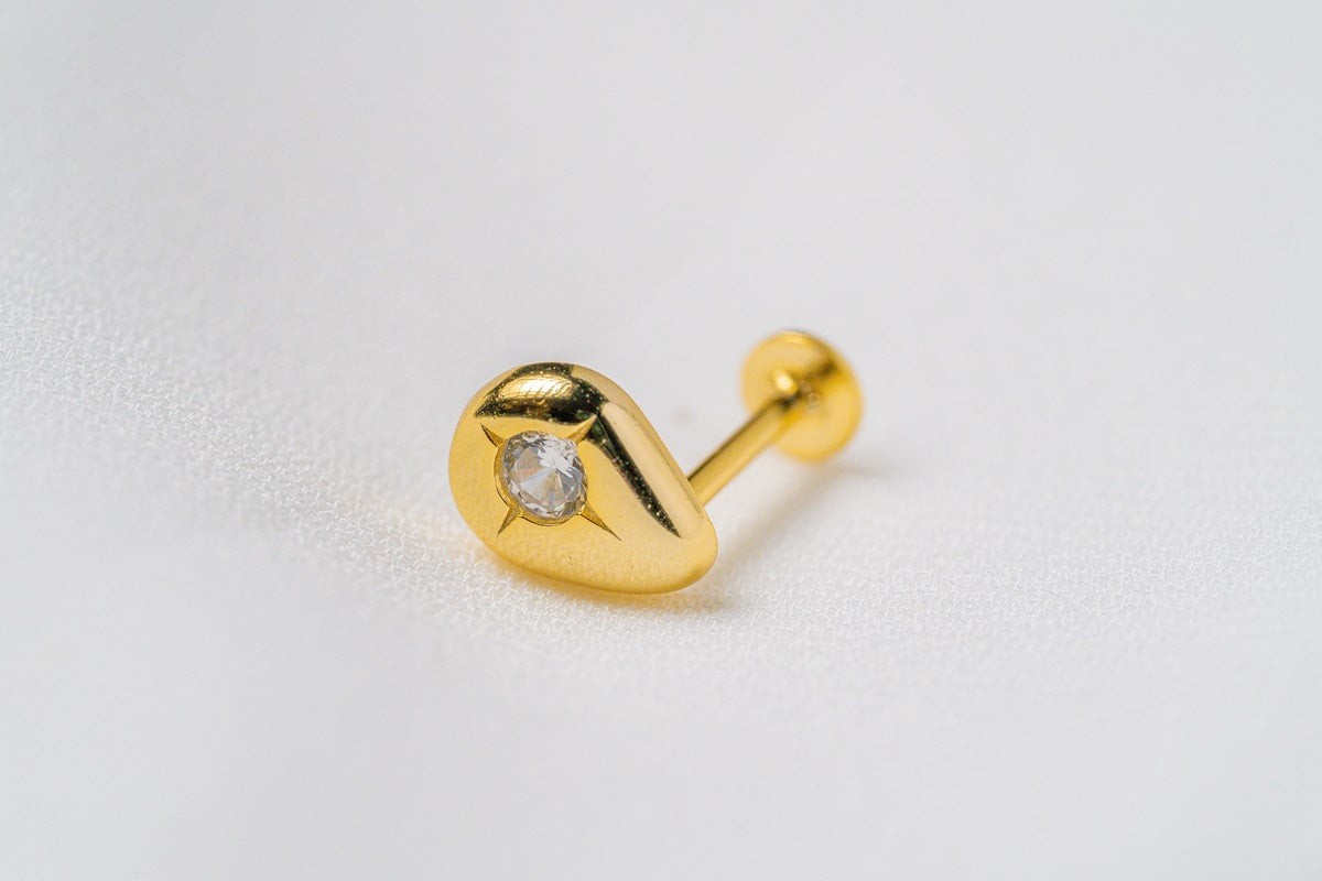 A gold raindrop shaped stud earring on a white background
