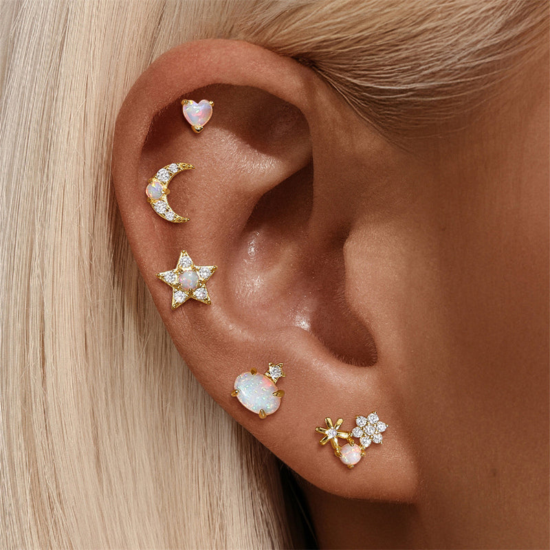 Close-up of an ear with multiple gold and gemstone earrings.