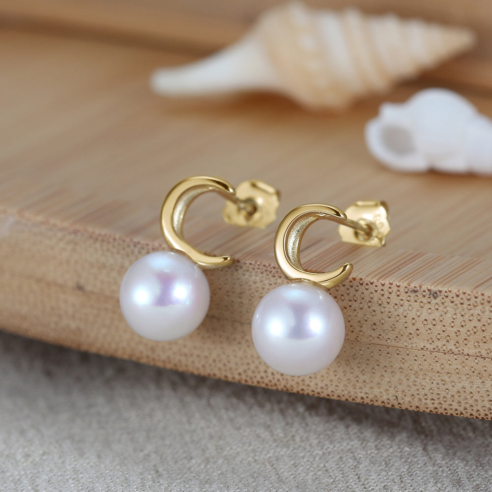 Pearl earrings with gold vermeil moon shape on a wooden surface