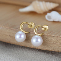 Pearl earrings with gold vermeil moon shape on a wooden surface